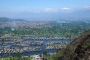 Blick über Hausboote auf dem Dalsee in Srinagar, Kaschmir, Indien, mit Bergen im Hintergrund